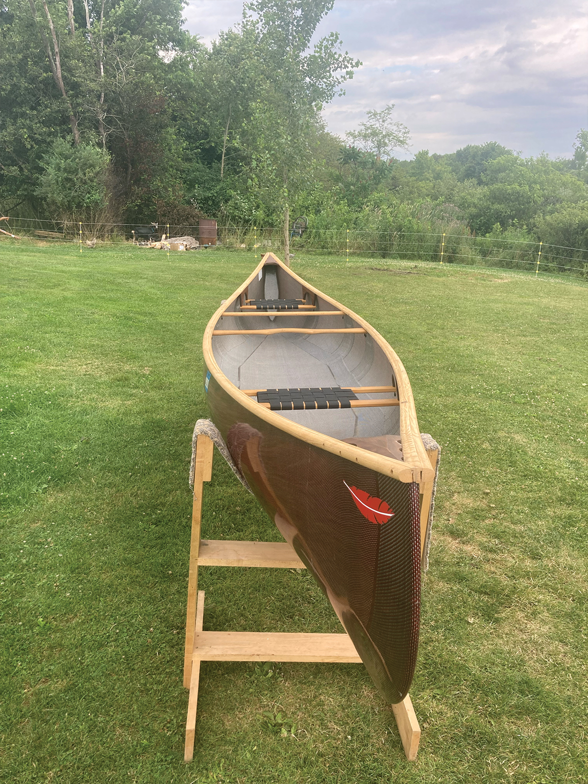 Starboard bow to stern view of Redfeather Prospector with red hull and ash gunwales