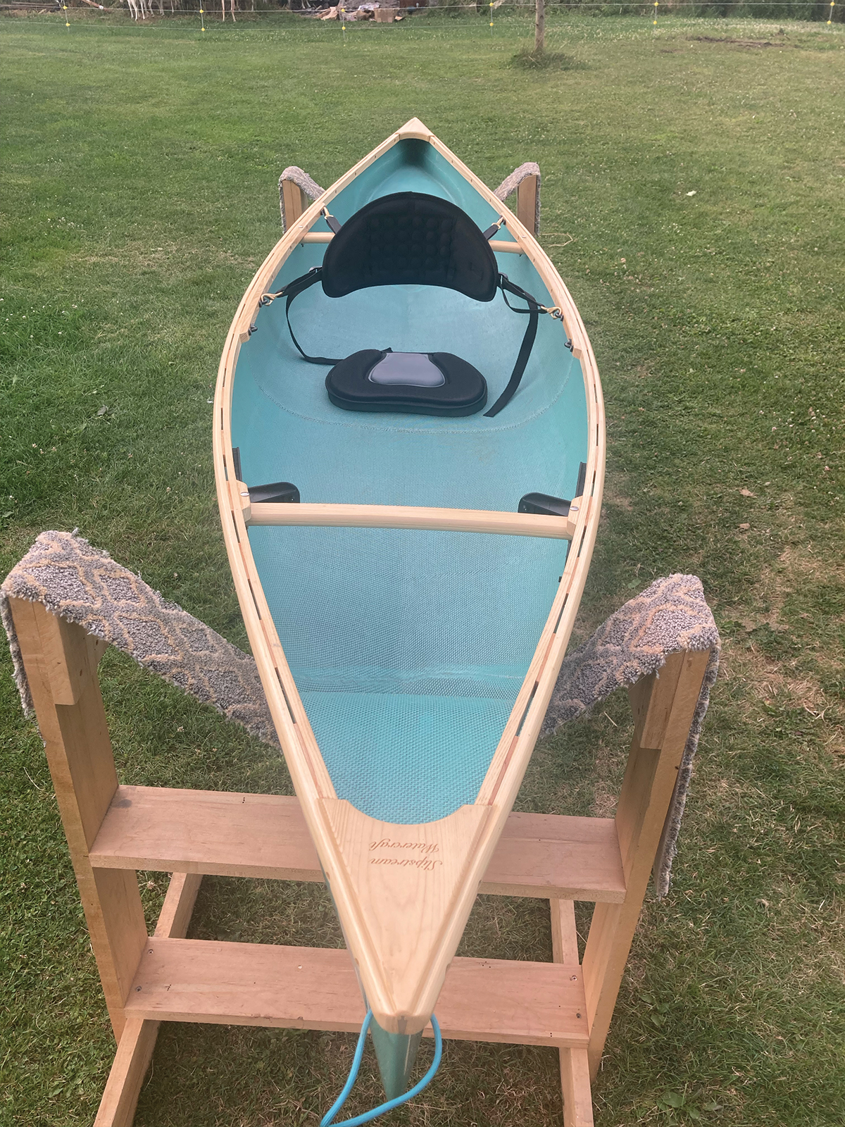 Overhead, bow to stern view of the Slipstream Wee Lassie Canoe with hand laminated teal hull and ash Gunwales