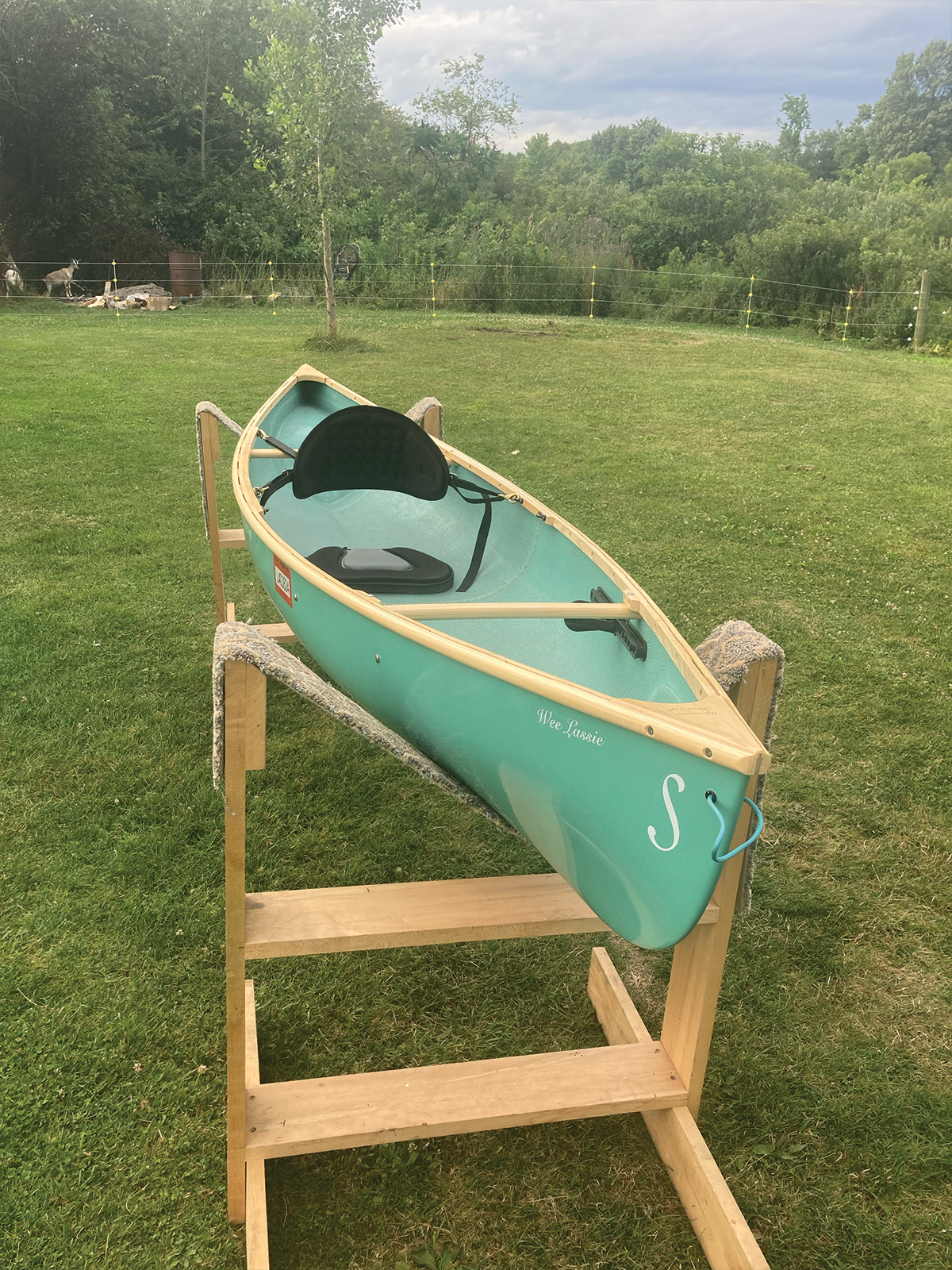 Starboard bow to stern view of the Slipstream Wee Lassie Canoe with hand laminated teal hull and ash Gunwales