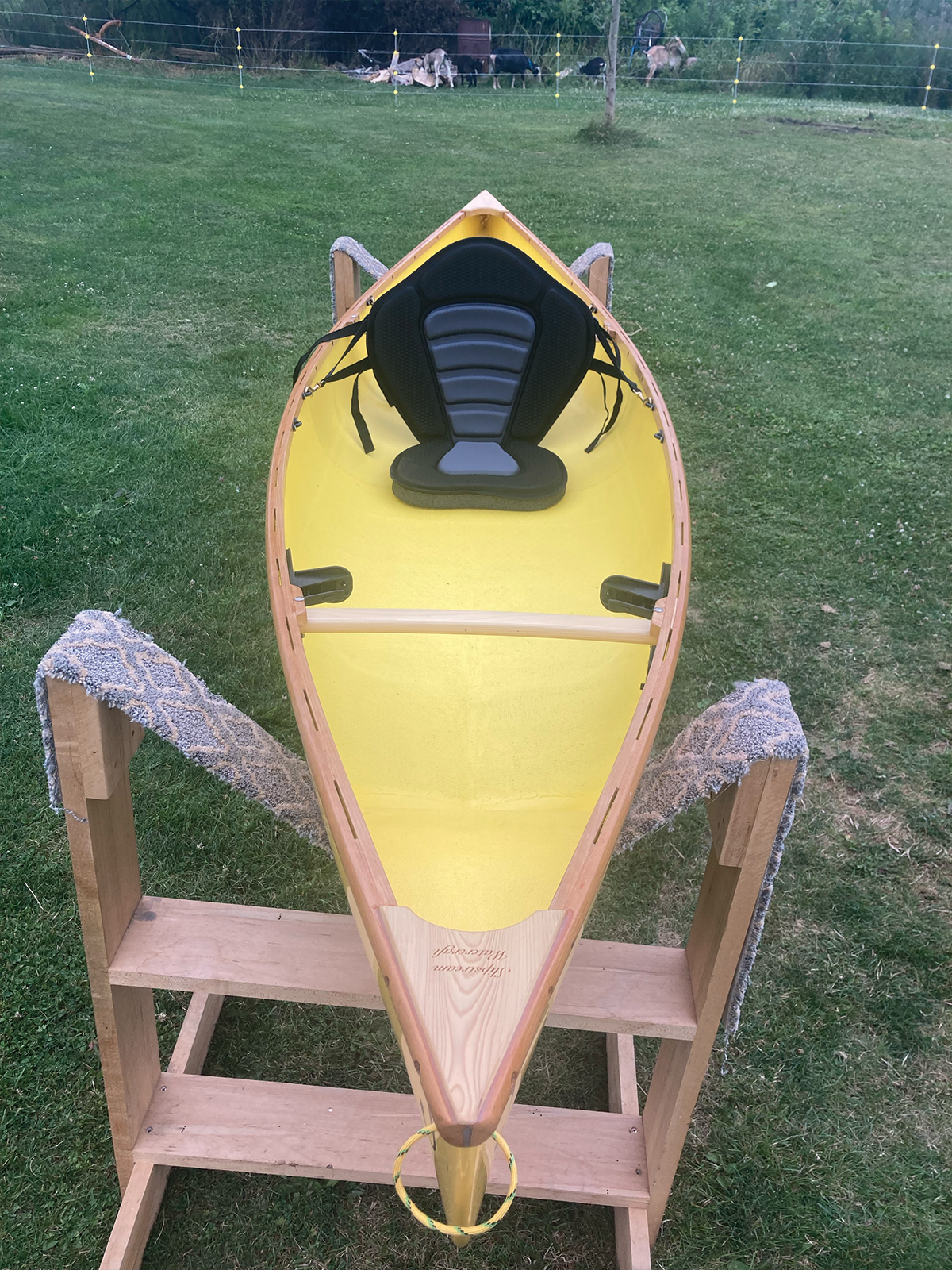 Overhead, bow to stern view of the Slipstream Wee Lassie Canoe with hand laminated egg yolk (yellow) hull and cherry Gunwales
