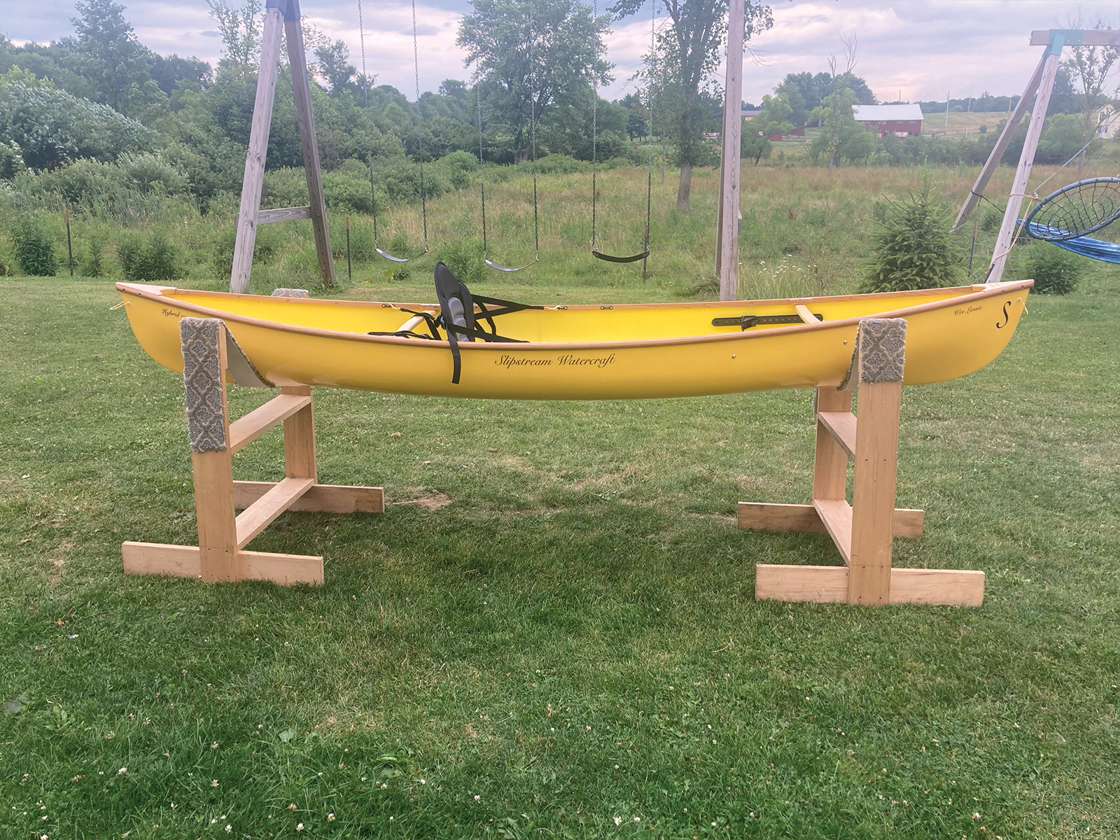 Starboard view of the Slipstream Wee Lassie Canoe with hand laminated egg yolk (yellow) hull and cherry Gunwales